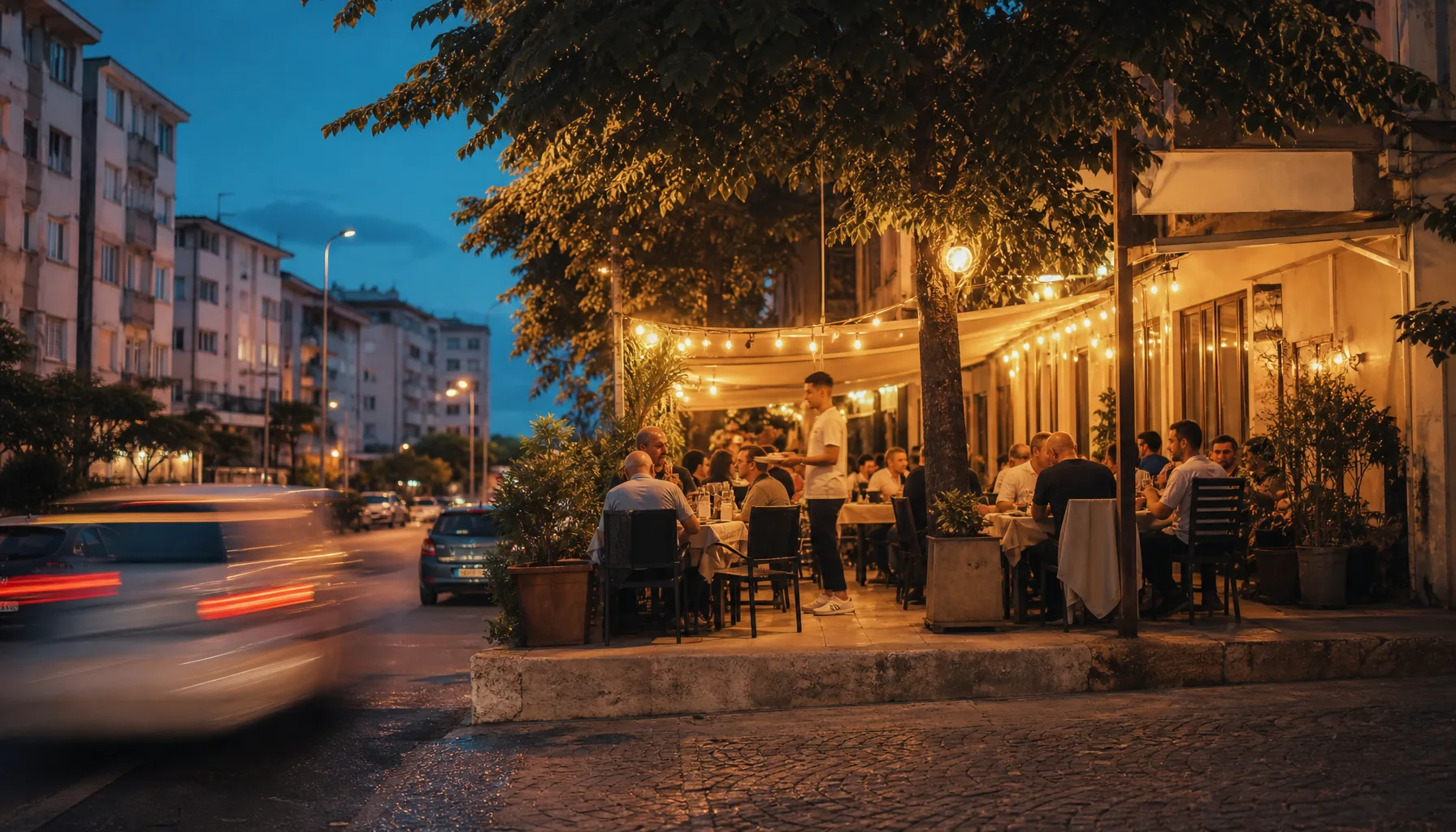 Akşam servisinde dolmaya başlayan bir restoran terası ve çevresindeki mahalle